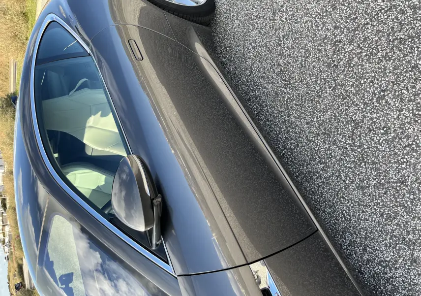 Vue latérale côté droit de la Jaguar F-TYPE II Coupé 2.0T 2018 en gris Corris avec jantes 19 pouces et intérieur clair visible.