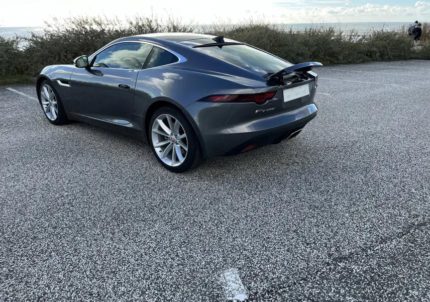Jaguar F-TYPE II Coupé gris Corris vue 3/4 arrière droit avec aileron arrière relevé et jantes 19 pouces.