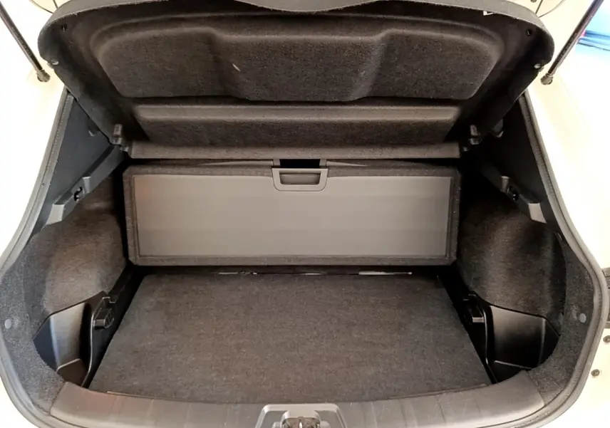 Coffre ouvert vu de face d'un Nissan Qashqai blanc, montrant l'espace de rangement et la tablette arrière.