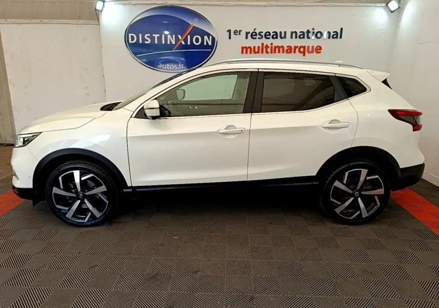 Vue de profil côté gauche d'un Nissan Qashqai blanc 2019 avec jantes alliage et toit spoiler dans un showroom.