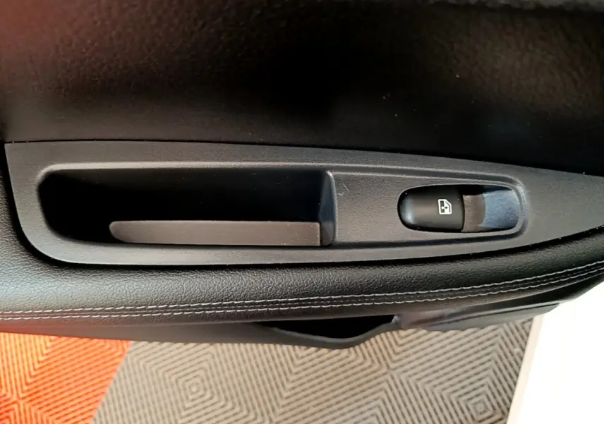 Détail de la commande de lève-vitre sur la porte intérieure noire d'un Nissan Qashqai blanc 2019.