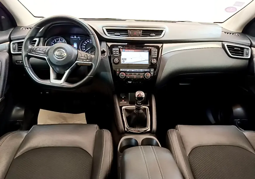 Vue intérieure frontale du tableau de bord noir du Nissan Qashqai 1.3 DIG-T 140 Tekna avec volant cuir et écran tactile central.