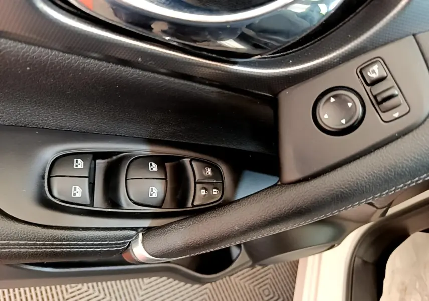 Gros plan sur la commande des vitres et rétroviseurs côté conducteur du Nissan Qashqai blanc, version 2019.