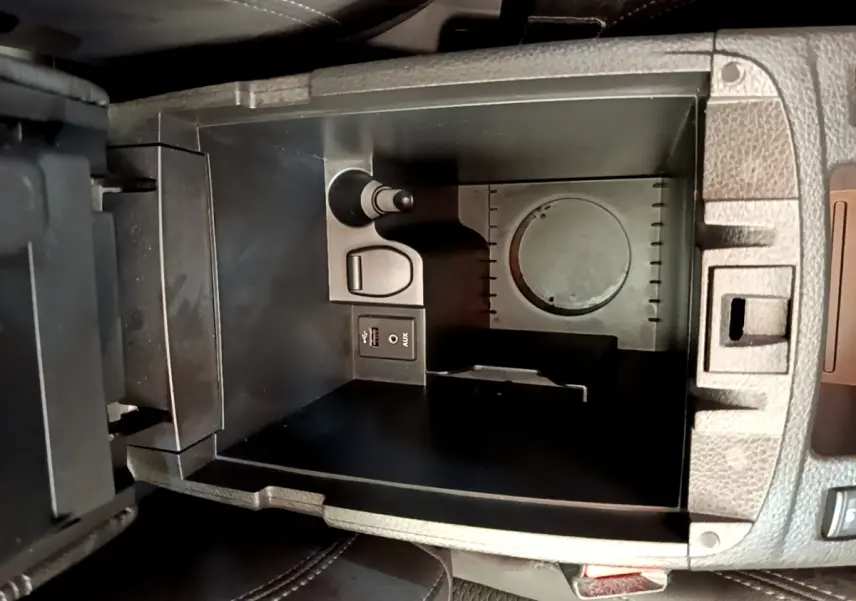Vue plongeante sur le rangement central noir du Nissan Qashqai 1.3 DIG-T 140 Tekna avec prise USB et AUX intégrées.