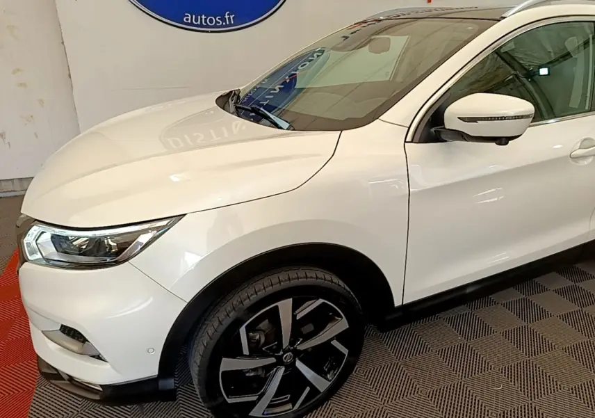 Vue 3/4 avant droit du Nissan Qashqai blanc 2019 avec jantes alliage noires et rétroviseur à clignotant intégré.