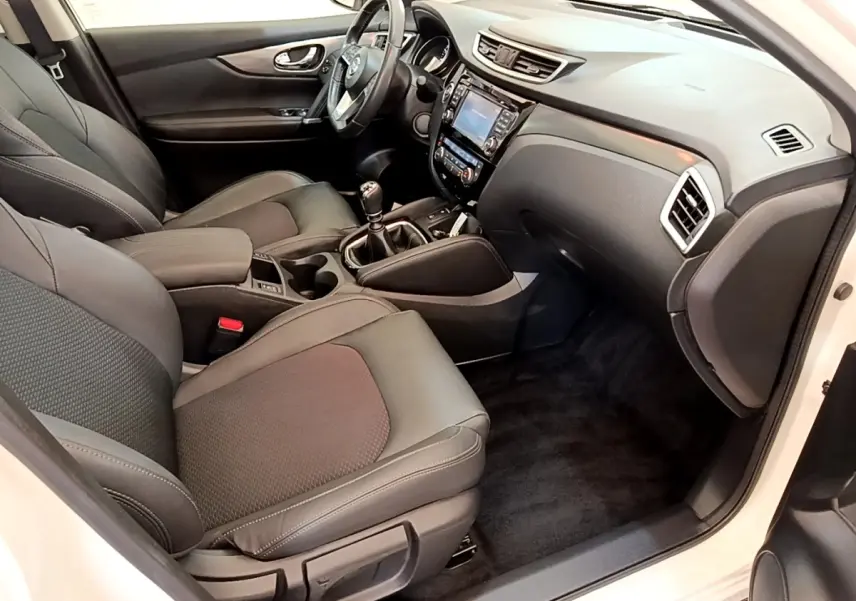 Intérieur avant droit du Nissan Qashqai blanc 2019, sièges noirs, tableau de bord avec écran tactile et boîte manuelle.