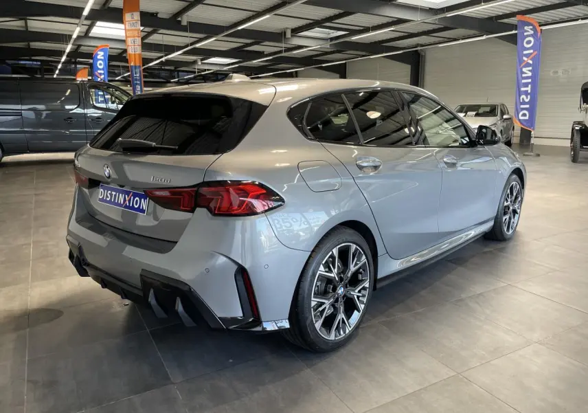 BMW Série 1 120d M Sport gris vue 3/4 arrière droit en intérieur avec jantes alliage et vitres teintées.