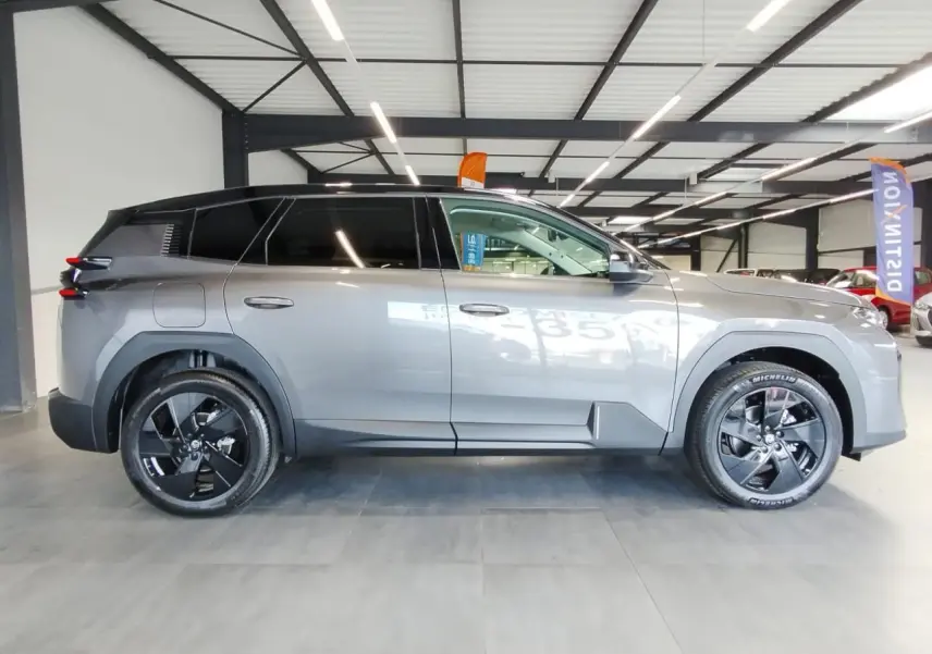 Vue de profil côté gauche d'un Citroën C5 Aircross gris platine avec jantes alliage noires en intérieur showroom.
