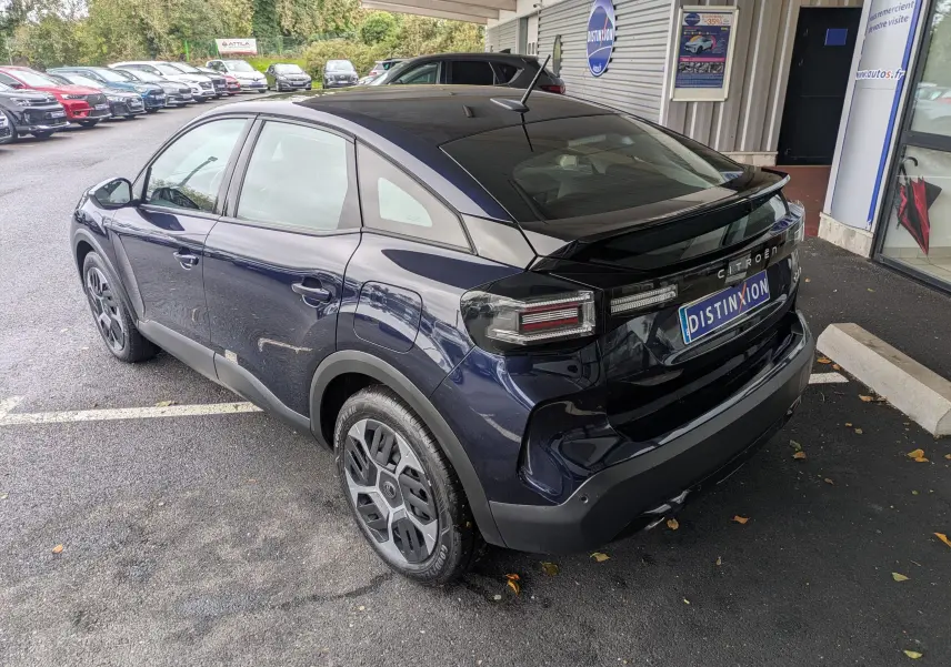 Vue 3/4 arrière droite d'une Citroën C4 Hybrid 145 E-DCS6 Plus bleu foncé avec jantes 18 pouces et feux arrière distinctifs.
