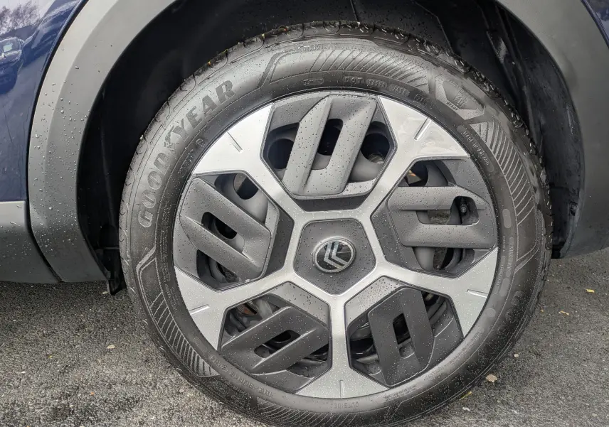 Gros plan sur la roue avant gauche d'une Citroën C4 Hybrid 145 E-DCS6 Plus bleu foncé avec jante tôle 18 pouces et pneus Goodyear.