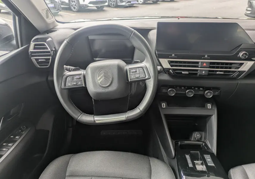 Vue intérieure avant centrée sur le volant et tableau de bord noir de la Citroën C4 Hybrid 145 E-DCS6 Plus 2025.