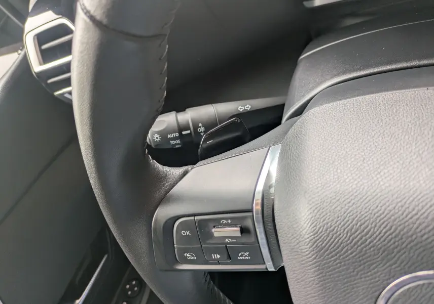 Vue intérieure côté conducteur de la Citroën C4 Hybrid 145 E-DCS6 Plus 2025, sellerie tissu/TEP gris et bleu foncé.