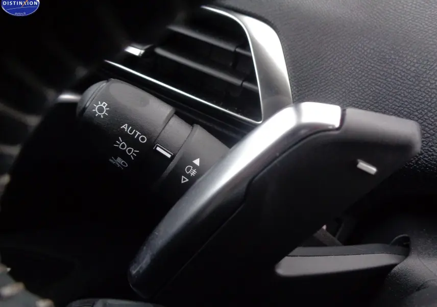 Gros plan sur la commande des feux et la palette de changement de vitesse dans l'habitacle du Peugeot 5008 gris platinium 2023.