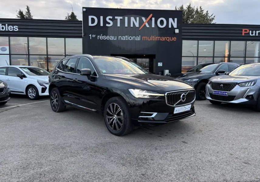 Volvo XC60 noir vue 3/4 avant droit sur parking devant concession multimarque Distinxion.
