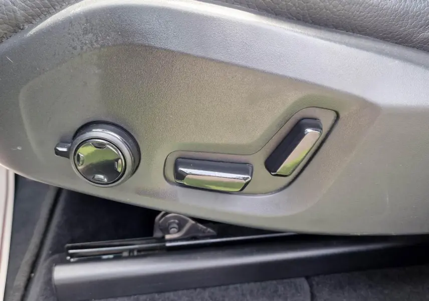 Commandes électriques de réglage du siège avant sur Volvo XC60 noir, vue rapprochée côté gauche.
