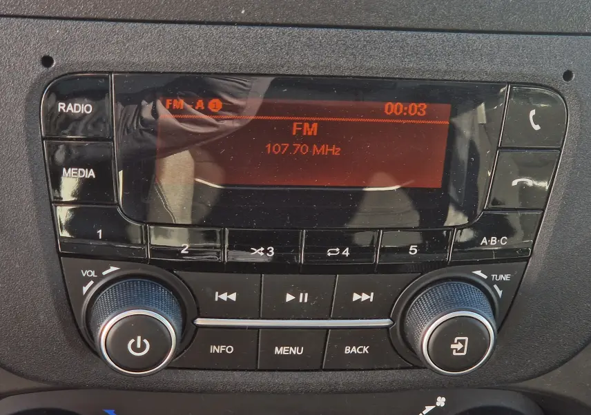 Vue rapprochée de la radio du tableau de bord du fourgon Iveco Daily blanc, affichant une fréquence FM.