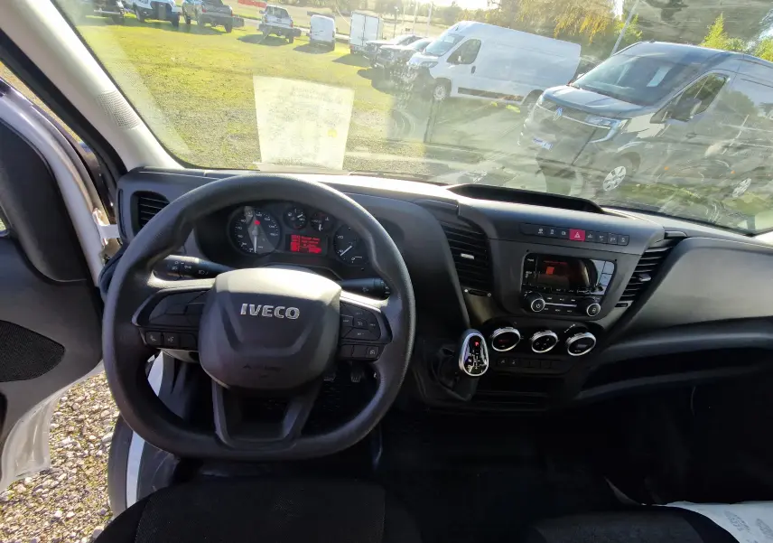 Vue intérieure du tableau de bord et volant IVECO Daily Fourgon blanc 2022 avec commandes au volant et console centrale noire.