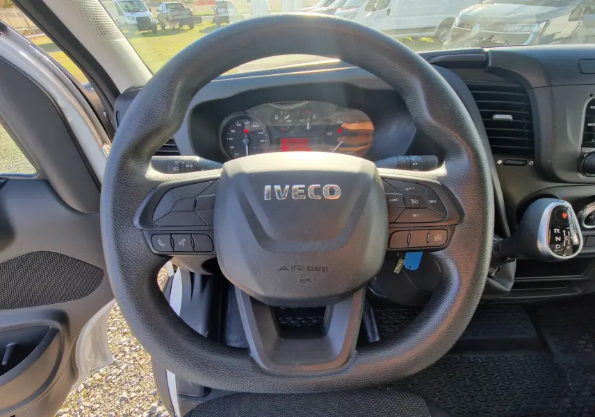 Vue intérieure centrée sur le volant noir IVECO du Daily Fourgon blanc 2022 avec levier de boîte auto visible à droite.