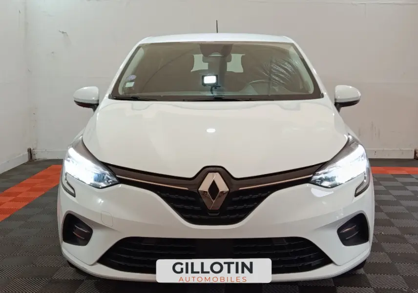 Vue frontale d'une Renault Clio Business TCe 90 blanche avec phares LED allumés dans un showroom.