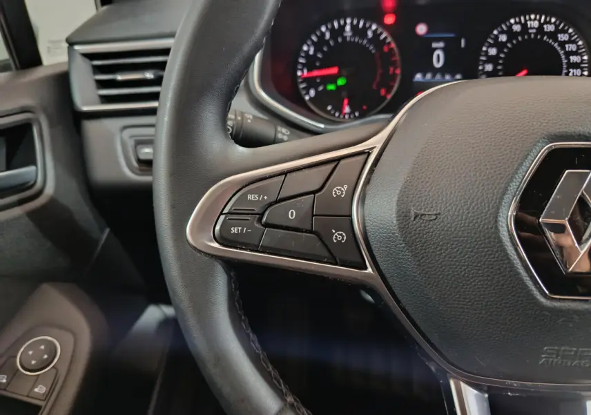Gros plan sur le volant cuir noir de la Renault Clio Business TCe 90 2021, avec commandes de régulateur de vitesse.