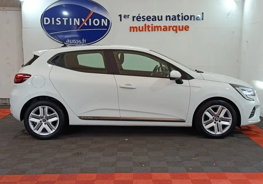 Profil droit d'une Renault Clio Business blanche 2021, avec jantes alliage et logo distinctif sous la porte arrière.