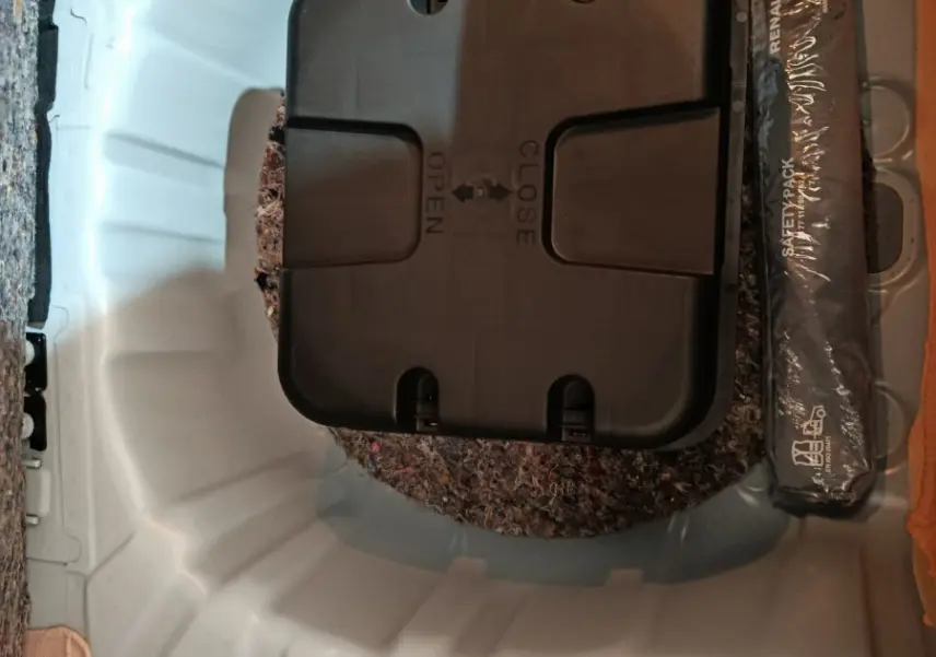 Vue plongeante sur le coffre blanc de la Renault Clio Business TCe 90, montrant le rangement sous tablette avec kit de sécurité.