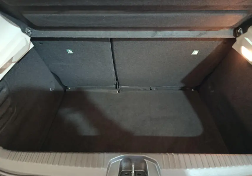 Coffre ouvert vu de face d'une Renault Clio Business TCe 90 blanche, intérieur noir et éclairage latéral.