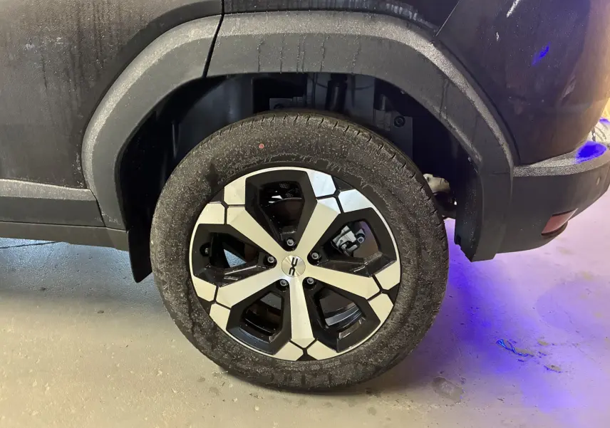 Vue rapprochée de l'aile arrière droite noire du Dacia Duster 1.6 Hybrid 140 Journey avec partie de la roue visible.