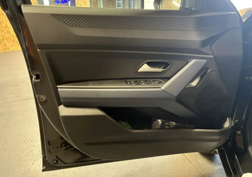 Vue intérieure de la porte avant gauche noire du Dacia Duster 1.6 Hybrid 140 Journey avec commandes électriques.