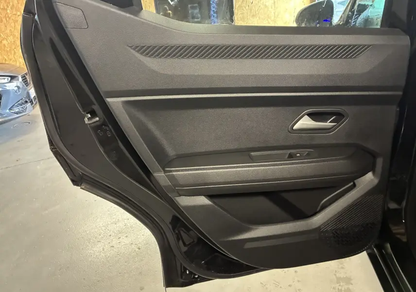 Vue rapprochée de la porte arrière gauche noire du Dacia Duster 1.6 Hybrid 140 Journey avec commande de vitre intégrée.