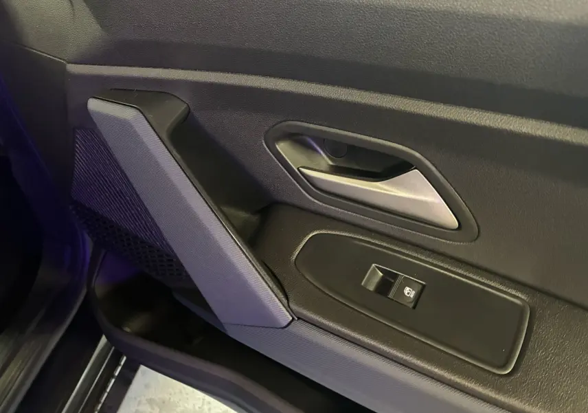 Gros plan sur la poignée intérieure et le bouton de lève-vitre côté gauche d’une porte noire du Dacia Duster 2025.