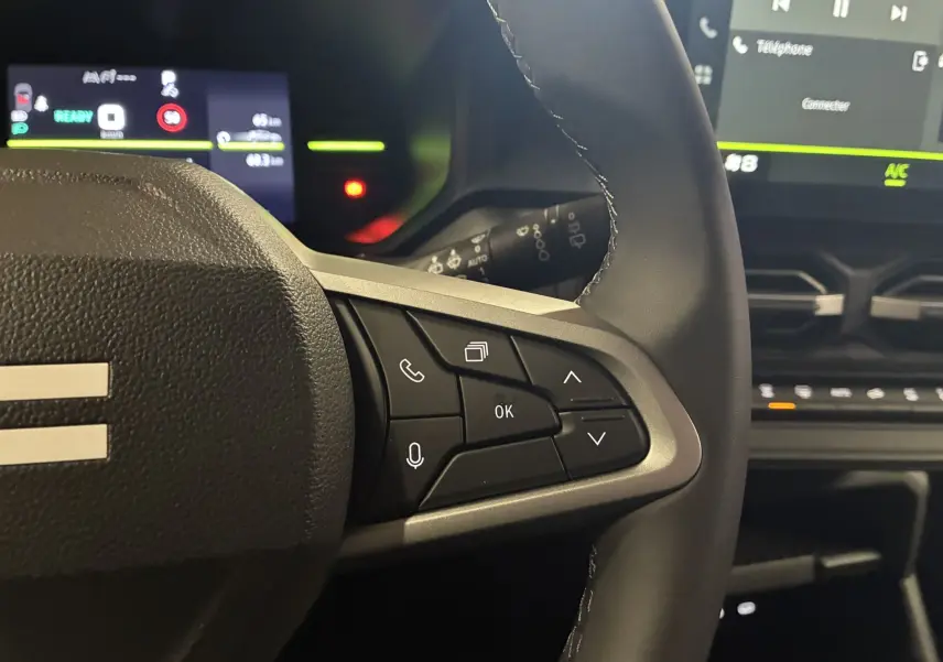 Gros plan sur les commandes au volant côté droit du Dacia Duster 1.6 Hybrid 140 Journey 2025, intérieur noir.