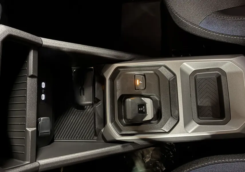 Vue rapprochée du levier de vitesses automatique et du frein de stationnement électrique sur la console centrale du Dacia Duster noir.