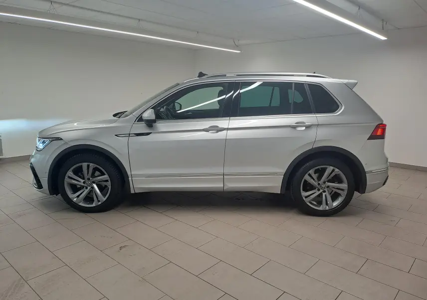 Vue de profil côté gauche du Volkswagen Tiguan 2024 en peinture métallisée Reflet d'Argent, avec jantes alliage et attelage escamotable.
