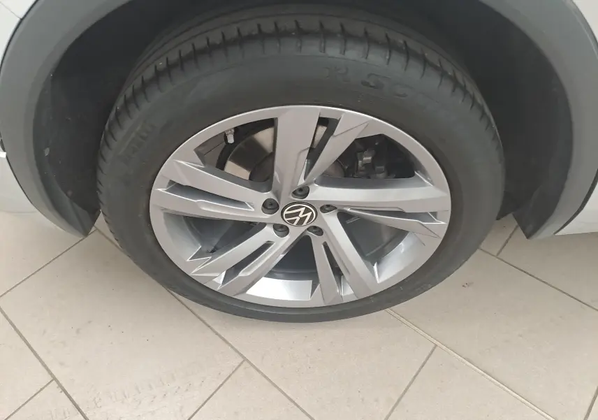 Gros plan sur la roue avant droite du Volkswagen Tiguan 2024 en Reflet d'Argent avec jante alliage à cinq branches doubles.