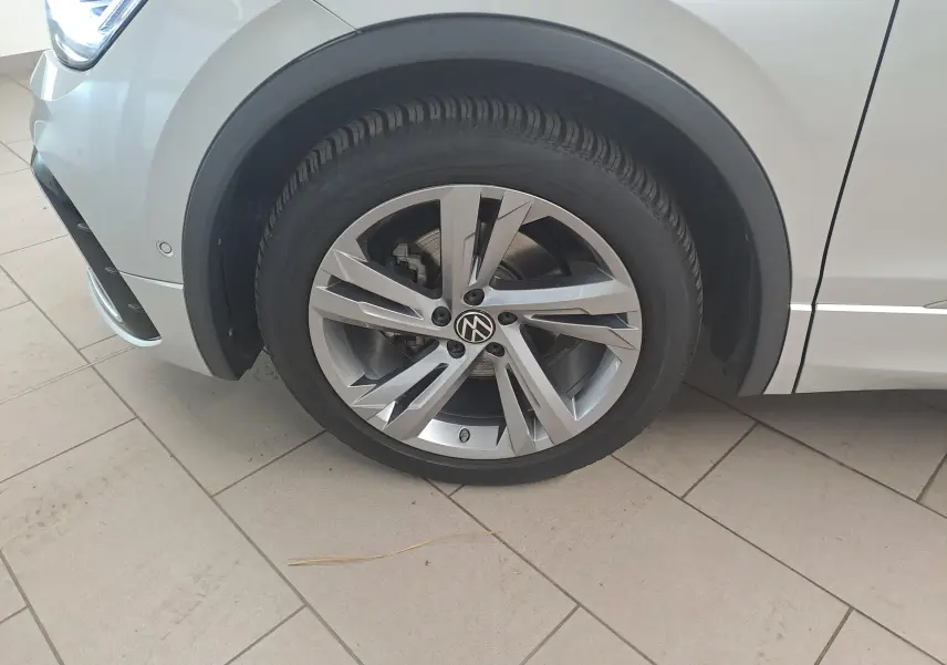 Gros plan sur la roue avant gauche d’un Volkswagen Tiguan 2024 argent avec jante alliage distinctive et partie du pare-chocs visible.