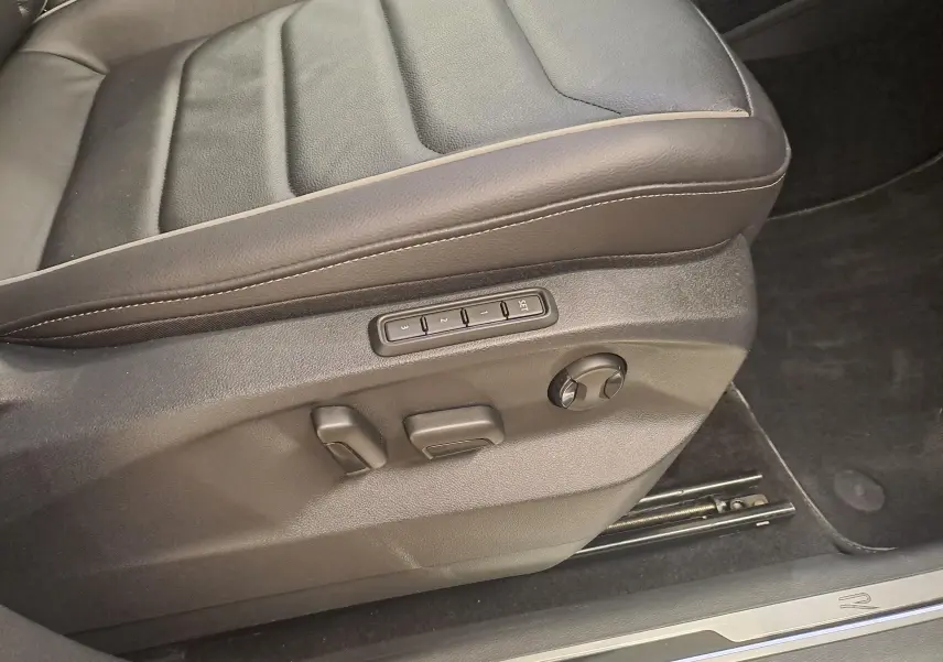 Gros plan sur le côté gauche du siège avant en cuir noir du Volkswagen Tiguan 2024 avec commandes électriques et surpiqûres contrastées.