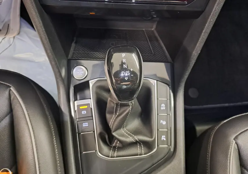Gros plan sur le levier de vitesses automatique du Volkswagen Tiguan 2024, entouré de boutons de contrôle et cuir noir.