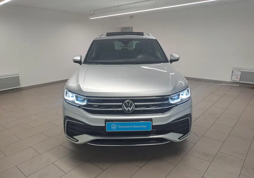 Vue frontale d'un Volkswagen Tiguan 2024 gris Reflet d'Argent avec phares LED allumés et calandre R-Line.