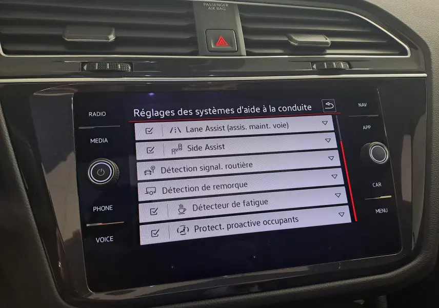 Écran tactile central du Volkswagen Tiguan 2024 affichant les réglages des aides à la conduite, intérieur noir.