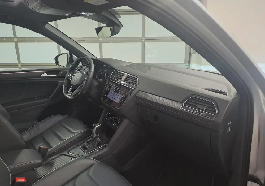 Vue intérieure côté conducteur du Volkswagen Tiguan 2024 en Reflet d'Argent, avec tableau de bord et volant multifonction.