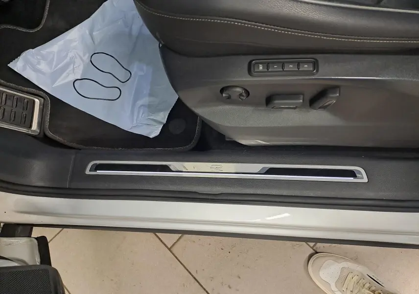 Vue rapprochée du seuil de porte côté conducteur du Volkswagen Tiguan 2024 en Reflet d'Argent avec réglages électriques du siège.