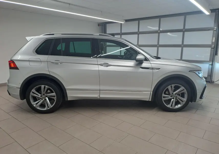 Vue de profil côté gauche d'un Volkswagen Tiguan 2024 en peinture métallisée Reflet d'Argent avec jantes alliage et attelage escamotable.