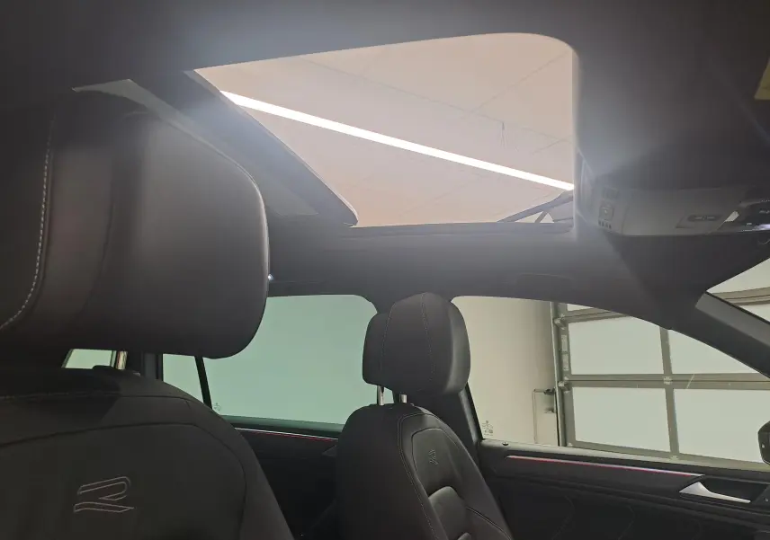 Vue intérieure du Volkswagen Tiguan 2024 avec toit ouvrant panoramique et sièges noirs R-Line en cuir.