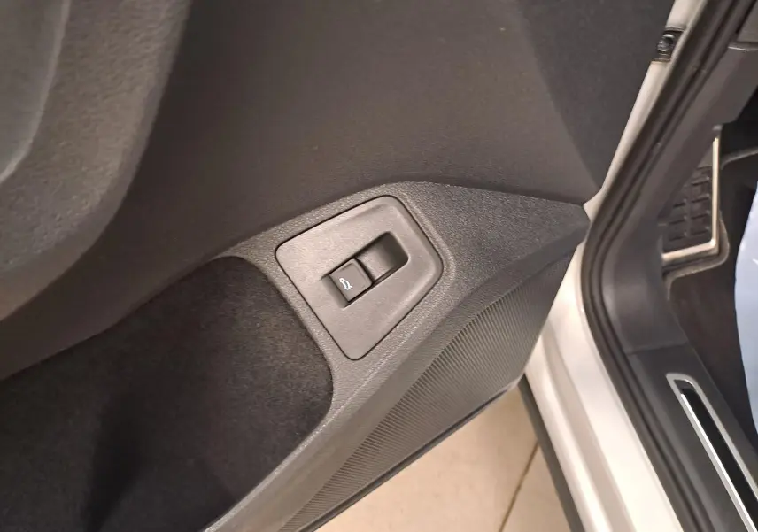 Gros plan sur le bouton d'ouverture du coffre intégré à la porte côté conducteur d'un Volkswagen Tiguan 2024 couleur Reflet d'Argent.