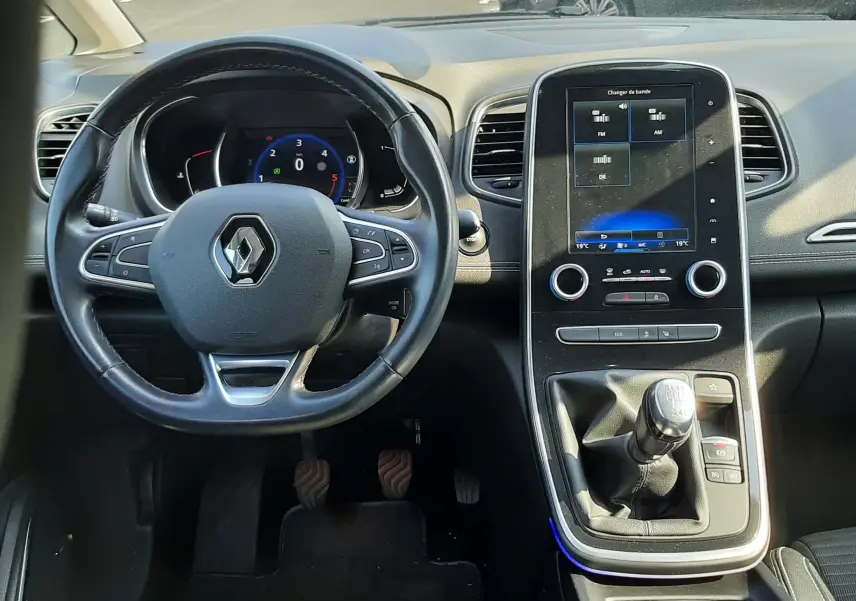 Vue intérieure du tableau de bord et volant de la Renault Scenic IV gris cassiopée avec boîte manuelle et écran tactile central.