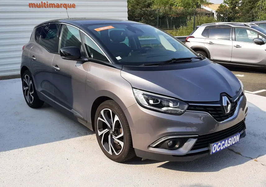 Renault Scénic IV gris Cassiopée avec toit noir, vue 3/4 avant, jantes alliage et calandre distinctive.