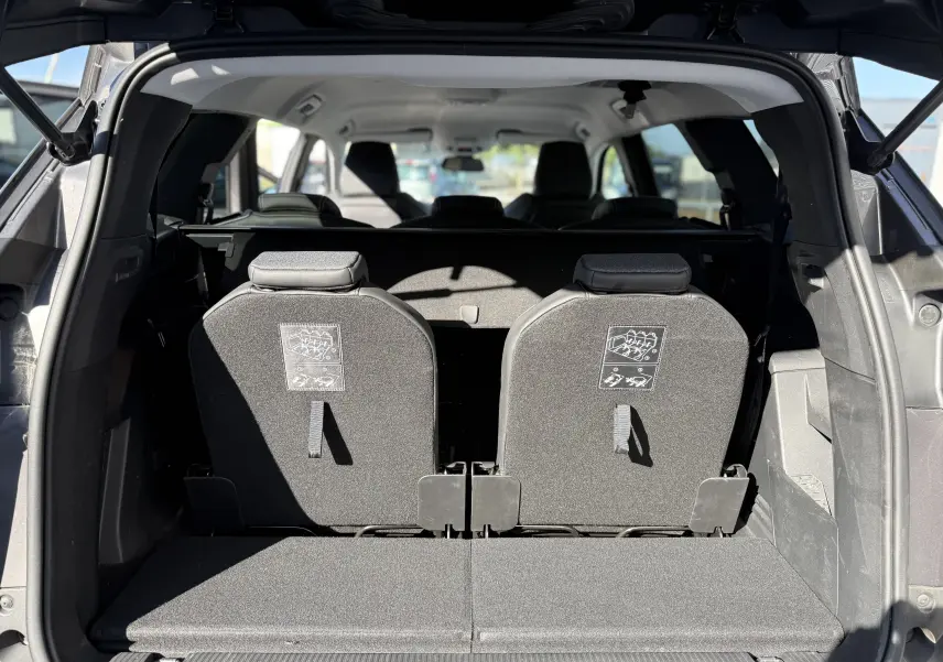 Vue arrière du coffre ouvert d’un Peugeot 5008 gris 2021, montrant les deux sièges arrière relevés et l’habitacle lumineux.