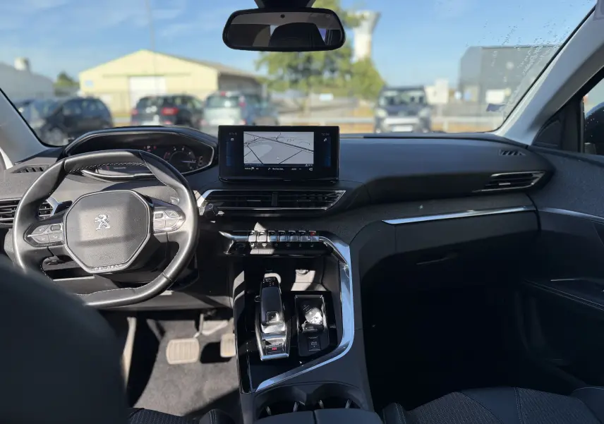 Vue intérieure avant du Peugeot 5008 gris 2021, avec tableau de bord moderne et écran tactile central affichant la navigation.