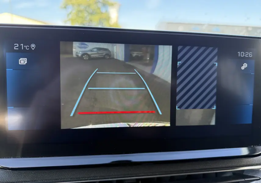 Vue écran caméra de recul du Peugeot 5008 gris 3/4 arrière droit avec lignes de guidage bleues et rouges.